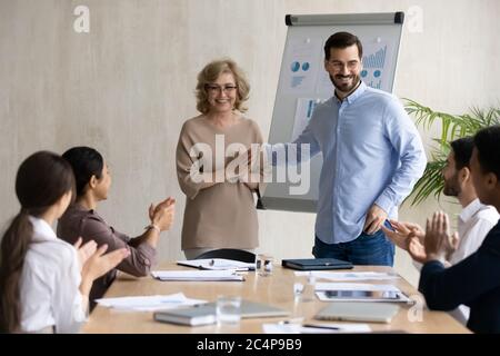 Un ejecutivo sonriente que presenta a un nuevo empleado contratado en una reunión corporativa Foto de stock