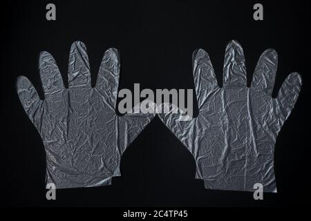 Un par de guantes de plástico desechables sobre un fondo negro. Concepto de protección. Foto de stock