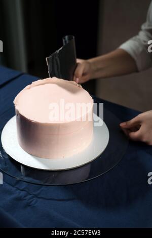 Chica Pastelería Chef, hace un pastel de boda con sus propias manos y aprieta la crema en las capas de pastel.