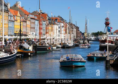 Barcos de paseo a lo largo del canal Nyhavn (New Harbor) bordeado de barcos y casas de antiguos comerciantes Foto de stock