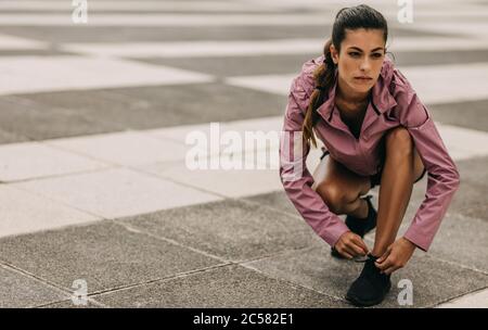 Mujer joven en ropa deportiva atar sus zapatillas antes de salir a