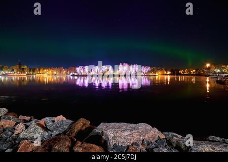 Vista de la isla Ilosaari por la noche sobre el fondo del cielo estrellado y aurora, Joensuu, Finlandia Foto de stock