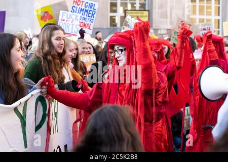Ataque climático global en la Plaza de San Pedro, Manchester, Reino Unido. Extinción rebelión los rebeldes rojos de circo invisibles se mantienen en manos de los manifestantes mientras caminan