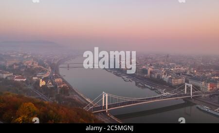Vista aérea del puente Elisabeth y el río Danubio tomada desde la colina Gellert al amanecer en la niebla en Budapest, Hungría.