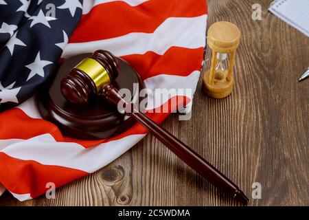 Reloj de arena que mide el cargo legal de los jueces de los Estados Unidos con el gavel de los jueces en la mesa de madera de la bandera estadounidense