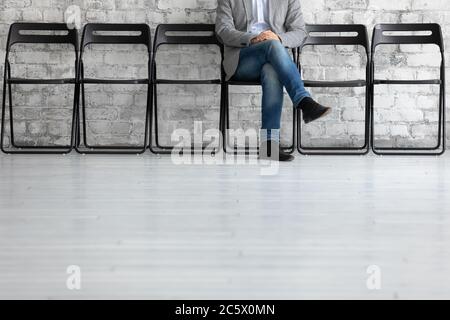 Hombre irreconocible sentado en la silla espera para la entrevista de trabajo de turno