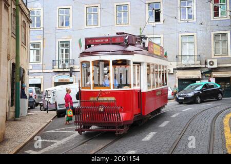 LISBOA, PORTUGAL - 4 DE JUNIO de 2018: La gente viaja en tranvía rojo por el distrito de Alfama, Lisboa, Portugal. La red de tranvías de Lisboa data de 1873 y es f Foto de stock