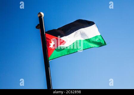 Una bandera jordana que revolotea en la brisa contra un cielo de verano. Foto de stock