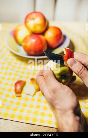Manos de cerca mientras se descascara la cáscara de manzana - ingrediente para la tarta de fruta Foto de stock