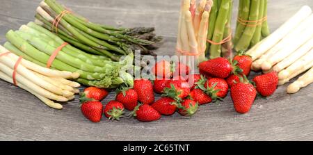 Grüne Sorgel, weiße Sorgel und frische Erdbeeren dekoriert auf einem rustikalen Holztisch Foto de stock