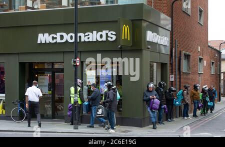 Los conductores de entrega se alinean fuera del McDonalds reabierto en Dalston el 13 de mayo de 2020 en Londres, Inglaterra. El primer ministro anunció una salida gradual del actual bloqueo, adoptado hace casi dos meses en un esfuerzo para frenar la propagación de Covid-19. Foto de stock