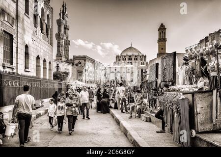 Multitudes caminando por la calle Azhar frente a la entrada principal de la Mezquita al Azhar y la mezquita Abu al Dahab en el Cairo Foto de stock