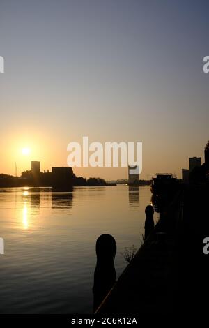 Silueta de edificios modernos en el río IJ en el verano justo antes de la puesta de sol en Amsterdam, Holanda