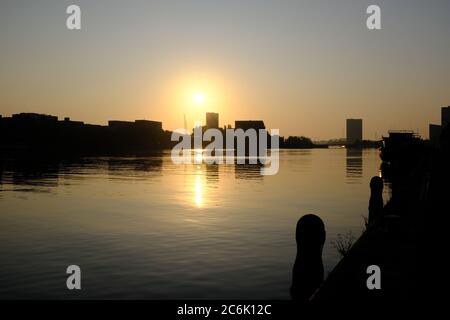 Silueta de edificios modernos en el río IJ en el verano justo antes de la puesta de sol en Amsterdam, Holanda
