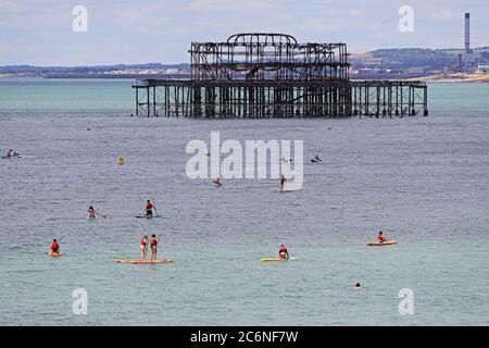 La gente disfruta del sol y el clima cálido en el mar de Brighton. Foto de stock