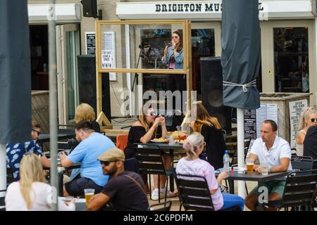 Brighton, Reino Unido. 11 de julio de 2020. Un cantante actúa detrás de una pantalla en el Brighton Music Hall durante el tiempo soleado en el paseo marítimo. La música al aire libre se ha relajado después de un largo período. Imagen de crédito: Julie Edwards/Alamy Live News Foto de stock