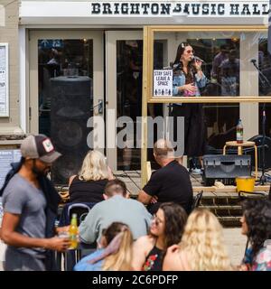 Brighton, Reino Unido. 11 de julio de 2020. Un cantante actúa detrás de una pantalla en el Brighton Music Hall durante el tiempo soleado en el paseo marítimo. La música al aire libre se ha relajado después de un largo período. Imagen de crédito: Julie Edwards/Alamy Live News Foto de stock