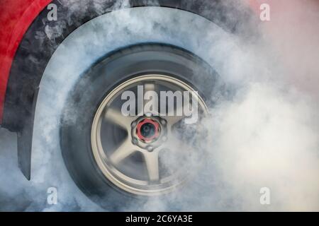 Drag Racing car sus neumáticos de goma quemaduras en preparación para la carrera Foto de stock