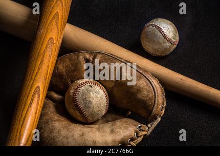 Dos pelotas de béisbol y un guante junto con un viejo y nuevo bate de béisbol. Todo menos el nuevo murciélago se rasca y se usa de años de amor del juego. Foto de stock