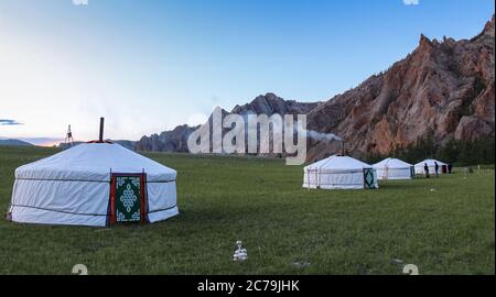 Una fila de gers mongol en un campamento al atardecer en una noche de verano, con humo de chimenea Foto de stock