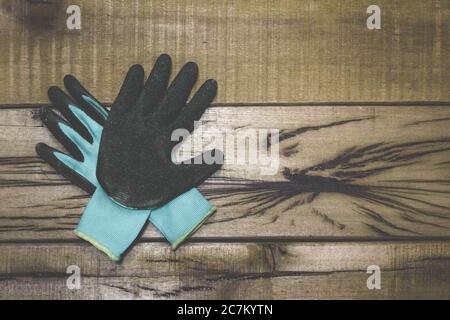 Primer plano de guantes de trabajo negros y azules en un banco de trabajo de madera con espacio para su texto