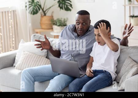 Problema informático. Black Boy y su abuelo miraron la pantalla del portátil Foto de stock