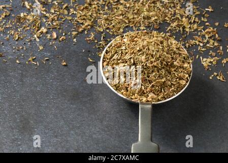 Hierba de orégano seca derramada de una cuchara Foto de stock
