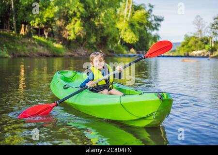 Feliz joven sosteniendo remar en un kayak en el río, disfrutando de un hermoso día de verano Foto de stock