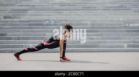 Chica negra con ropa deportiva sentada en las escaleras