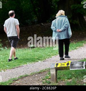 Un hombre y una mujer caminan a 2 m de distancia en un camino en el parque rural East Carlton, Corby, julio de 2020, debido a la epidemia de coronavirus. Foto de stock
