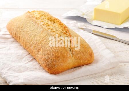 Pan de ciabatta fresco sobre una servilleta de lino blanco sobre una mesa de madera. Cocina tradicional italiana. Horneando pan de trigo con levadura o masa fermentada.