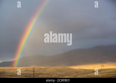 Un arco iris doble se extiende a través del paisaje en la carretera de Goris a Shaki en la esquina suroeste de Armenia. Foto de stock