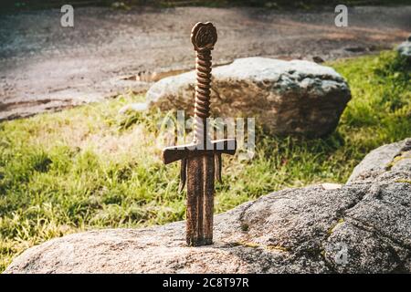 Espada famosa excalibur del rey Arturo pegado en roca. Armas de filo de la leyenda Pro rey Arthur. Foto de stock