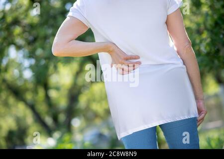 Mujer que siente un dolor en la parte baja de la espalda Foto de stock
