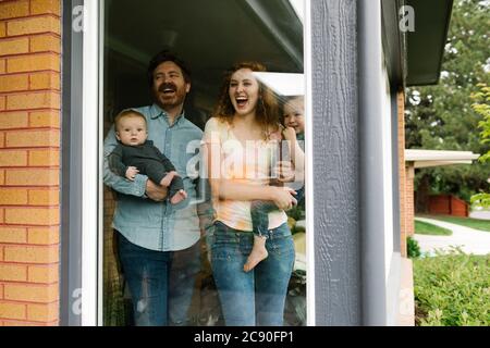 Estados Unidos, Utah, Salt Lake City, Familia con niños (6-11 meses, 2-3) mirando a través de la ventana Foto de stock