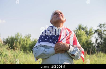 El patriótico anciano celebra el día de la independencia de los estados unidos el 4 de julio con una bandera nacional en sus manos. Día de la Constitución y la Ciudadanía. Gran Nacional Foto de stock