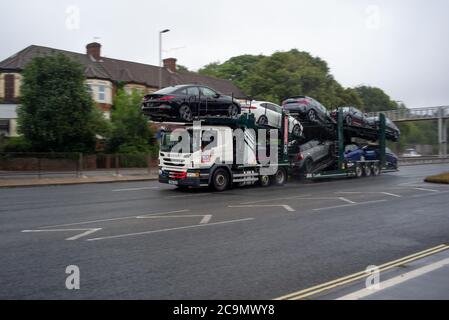 Un transportista lleno de BMW hacer coches minis y BMWs conducir a lo largo de la carretera cerca de Southampton Docks. Foto de stock