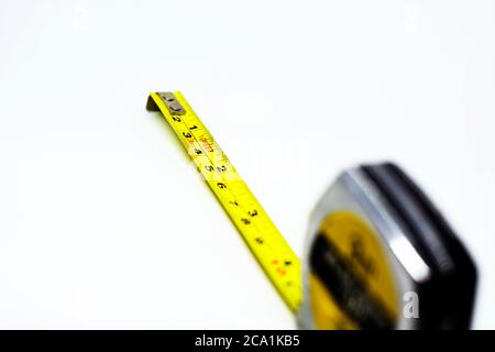 cinta de medición metálica amarilla retráctil aislada sobre fondo blanco. Medidas expresadas en centímetros y pies. Instrumento de medición Foto de stock