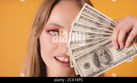  Retrato de mujer con maquillaje que cubre la mitad de la cara con dólares. Foto de alta calidad Fotografía de stock