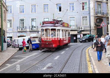LISBOA, PORTUGAL - 4 DE JUNIO de 2018: La gente viaja en tranvía rojo por el distrito de Alfama, Lisboa, Portugal. La red de tranvías de Lisboa data de 1873 y es f Foto de stock