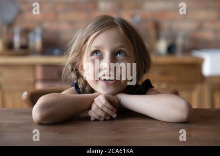 Una chica linda se sienta a la mesa en la cocina cantando Foto de stock