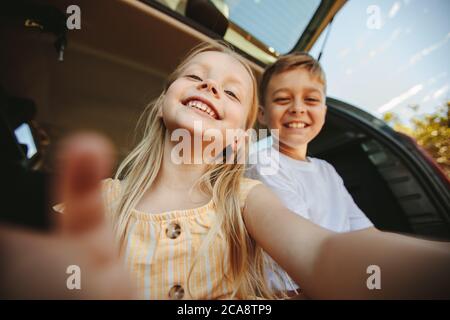 PDV de niña jugando con el dispositivo. Felices niños tomando selfie con el dispositivo móvil.