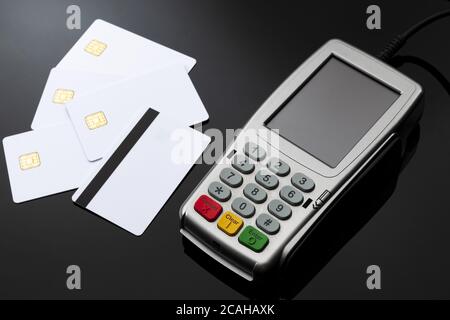 Caja de pago, transacción financiera y concepto de pagos electrónicos con lector de tarjetas de crédito y débito con teclado de goma junto a blanco mag Foto de stock