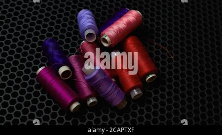Hilos de costura multicolor sobre un fondo oscuro de primer plano desde arriba Foto de stock