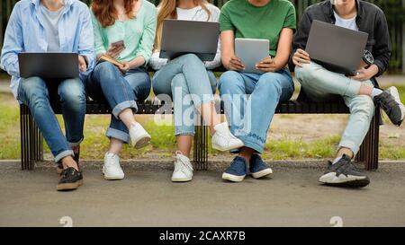 Los estudiantes pastime. Grupo de jóvenes que pasan tiempo con dispositivos electrónicos al aire libre