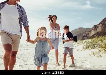 Feliz familia de vacaciones de correr juntos en la playa. Los niños se divierten con sus padres en las vacaciones de playa.