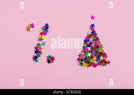 Símbolo de descuento y un árbol de Navidad de estrellas multicolor sobre un fondo rosa. Un signo de porcentaje, ventas de Navidad