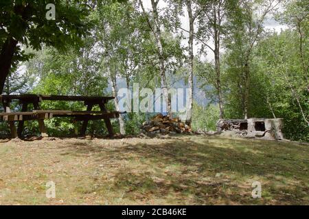 Una zona de nic pic en los alpes italianos con madera mesa y parrilla de piedra cruda Foto de stock