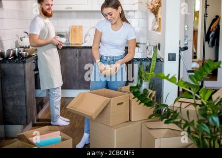 una pareja joven y hermosa casada caucásica se mudó a una casa nueva, desembalan las cajas en casa juntas Foto de stock