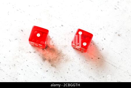 Dos dados rojos mostrando Ace Deuce (Número 1 y 2) tiro al techo sobre pizarra blanca Foto de stock